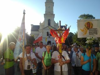 Gotowe do wyjścia czoło pielgrzymki na tle kościoła pw. Narodzenia Najświętszej Marii Panny w Dobrej